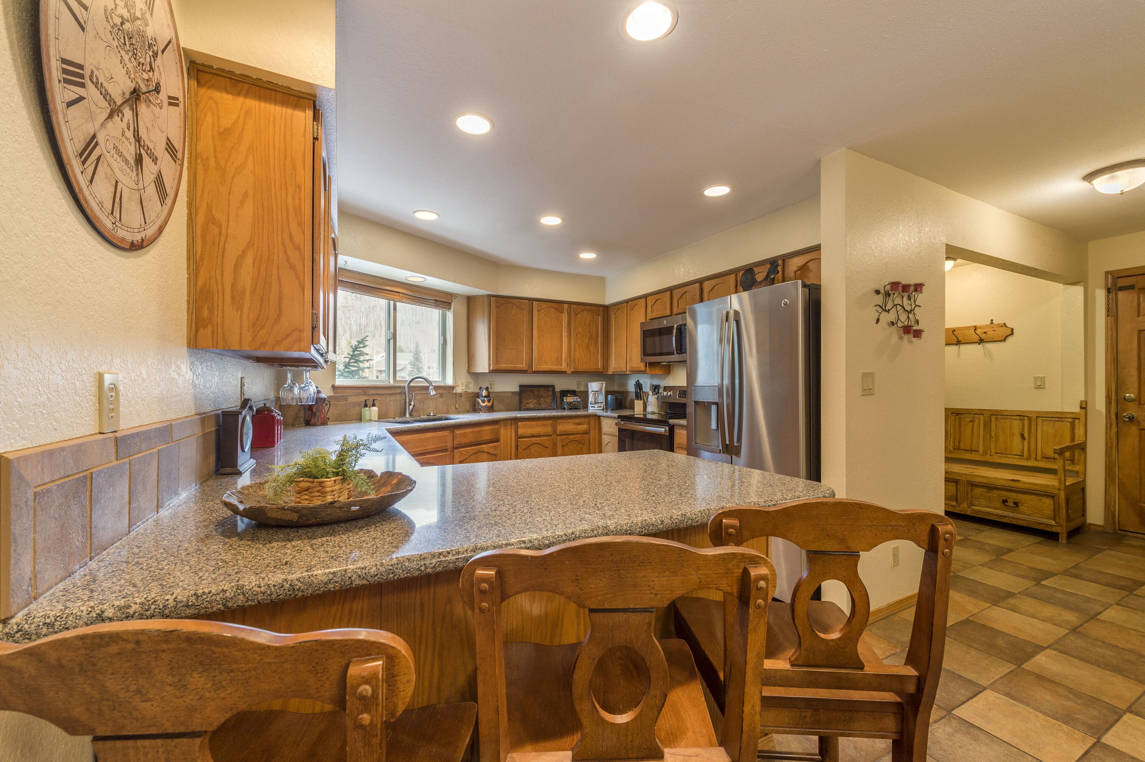 A kitchen with wooden cabinets, granite countertops, and a large island with chairs.