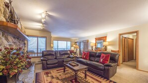 A living room with a stone fireplace, leather sofas, a coffee table, and a patterned rug. - Large 3 BR/3 BA Near Mountain House Lifts; Private Hot Tub in unit; 7 beds (Keystone)