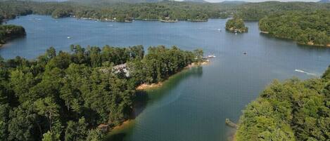 Vista aérea de un lago rodeado de bosque denso, con varias embarcaciones y un muelle.