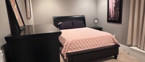 Un dormitorio con cama, cómoda, ventilador de techo y un cuadro en la pared.