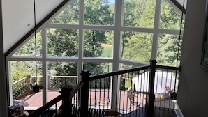 Een kamer met een groot raam dat uitzicht biedt op een terras en groen.