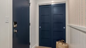 En hall med en mörkblå dörr, en ljusströmbrytare och en brun papperspåse på golvet.