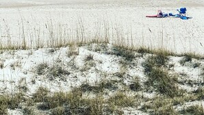 Una playa con arena, algunas personas y sillas de playa.