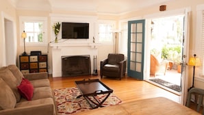 A living room with a fireplace, a sofa, a chair, and a television. - "LOCATION! LOCATION! West Beach. Beach.  New Owner. (Santa Barbara)