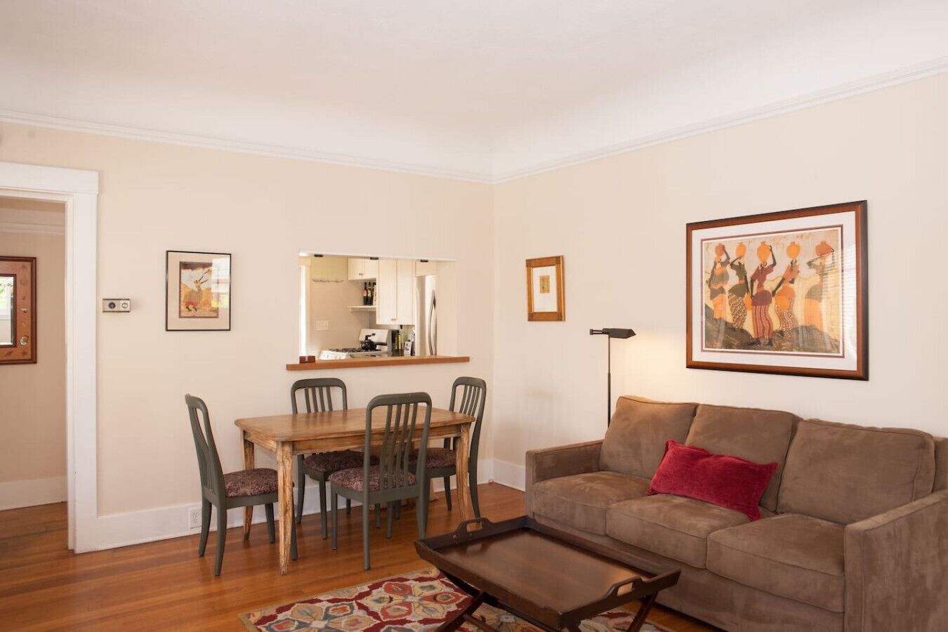 A living room with a brown sofa, a wooden coffee table, and a dining area with a wooden table and chairs.