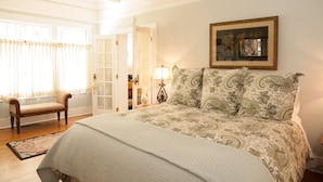 A bedroom with a large bed, a chair, a lamp, and a framed picture on the wall. - "LOCATION! LOCATION! West Beach. Beach.  New Owner. (Santa Barbara)