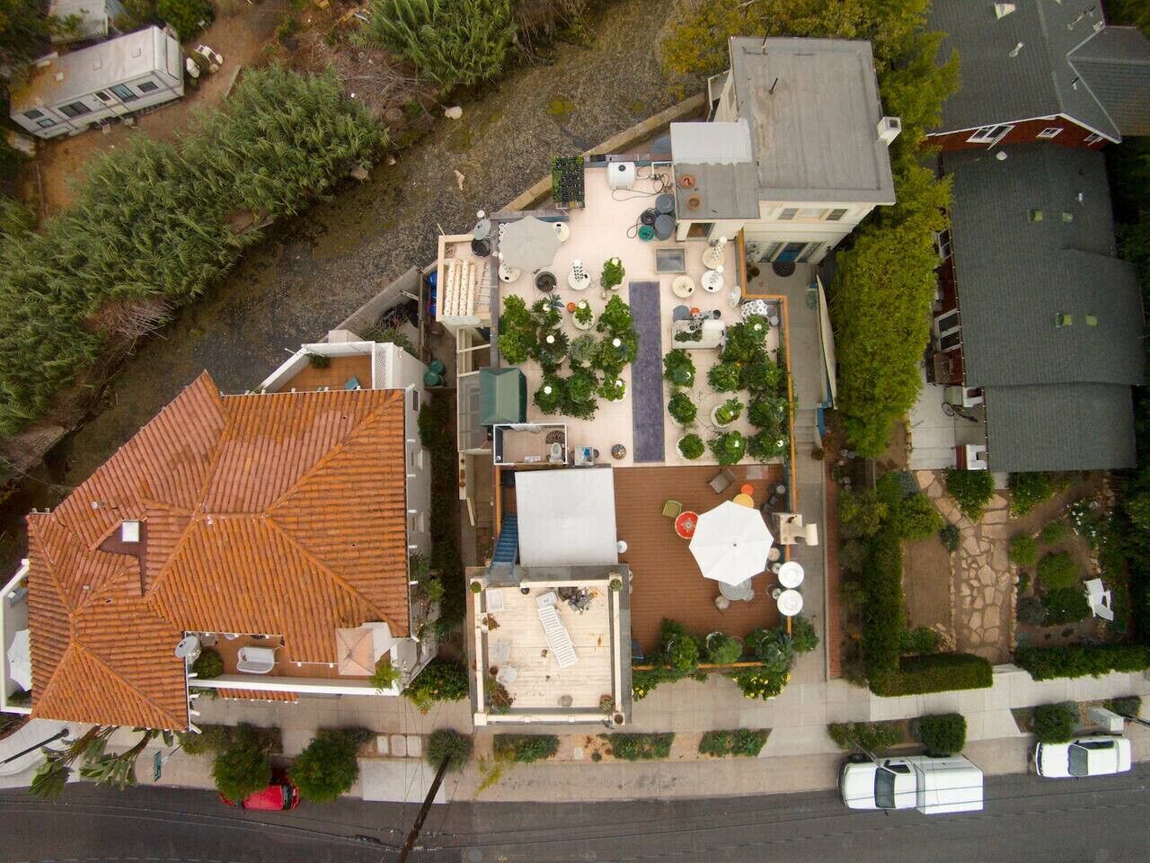 Vista aérea de una propiedad residencial con techo de tejas, zona de patio con mobiliario exterior y jardín.
