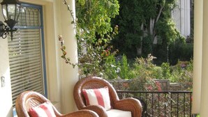 A covered porch with wicker furniture, a potted plant, and a view of greenery. - "LOCATION! LOCATION! West Beach. Beach.  New Owner. (Santa Barbara)
