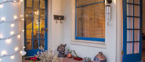 A front door with blue shutters, a light fixture, and potted plants.