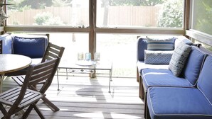 Un espace extérieur abrité, aménagé avec une table et des chaises, un canapé et un ventilateur de plafond.