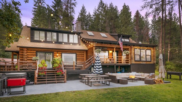 A log cabin with a deck, outdoor seating, and a fire pit.