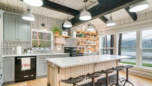 A modern kitchen with a large island, bar stools, and a view of a lake.