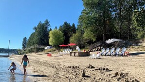 A beach with clear water, a wooden deck, and beach chairs.