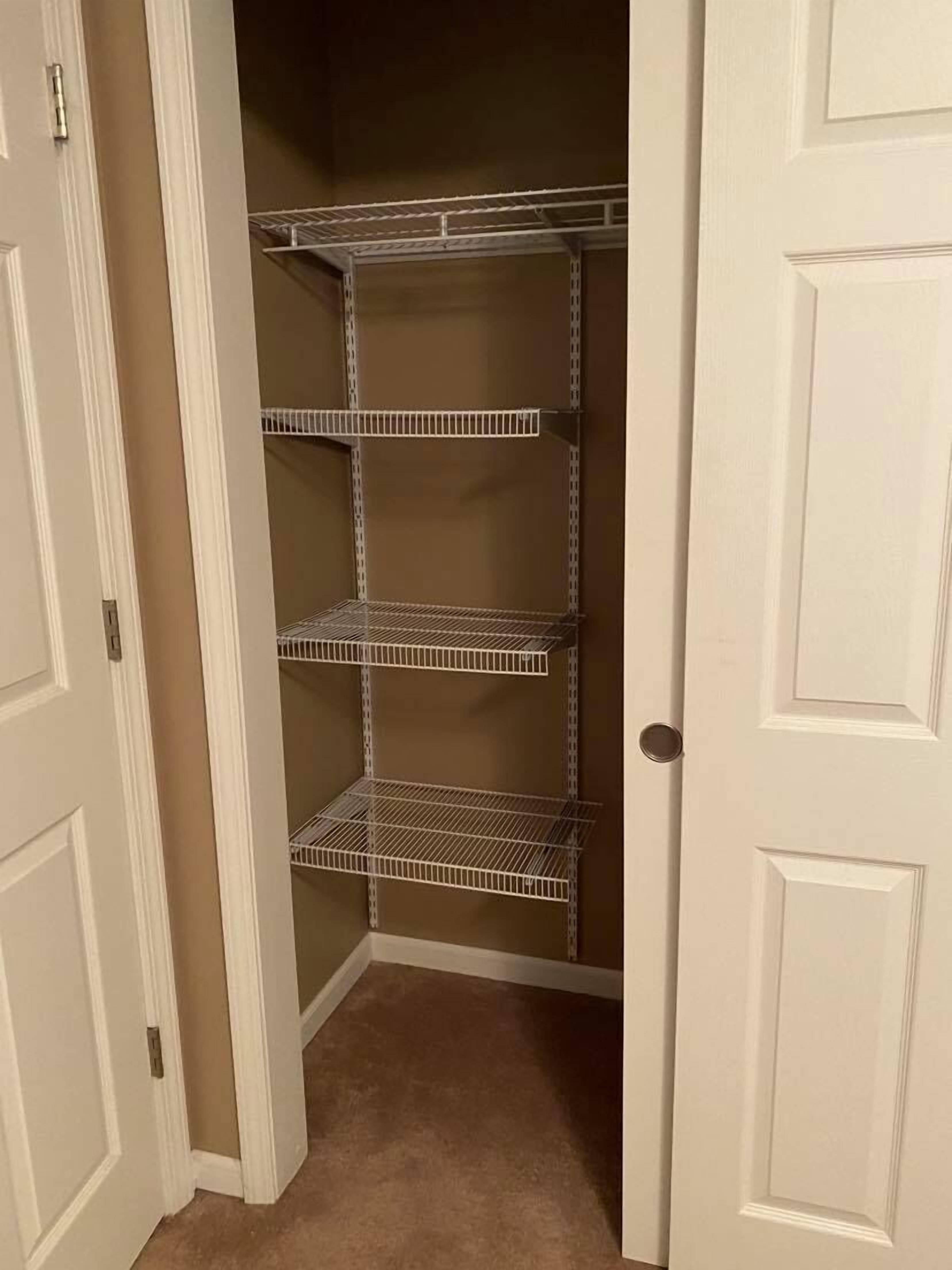 A closet with white doors and metal shelving units.