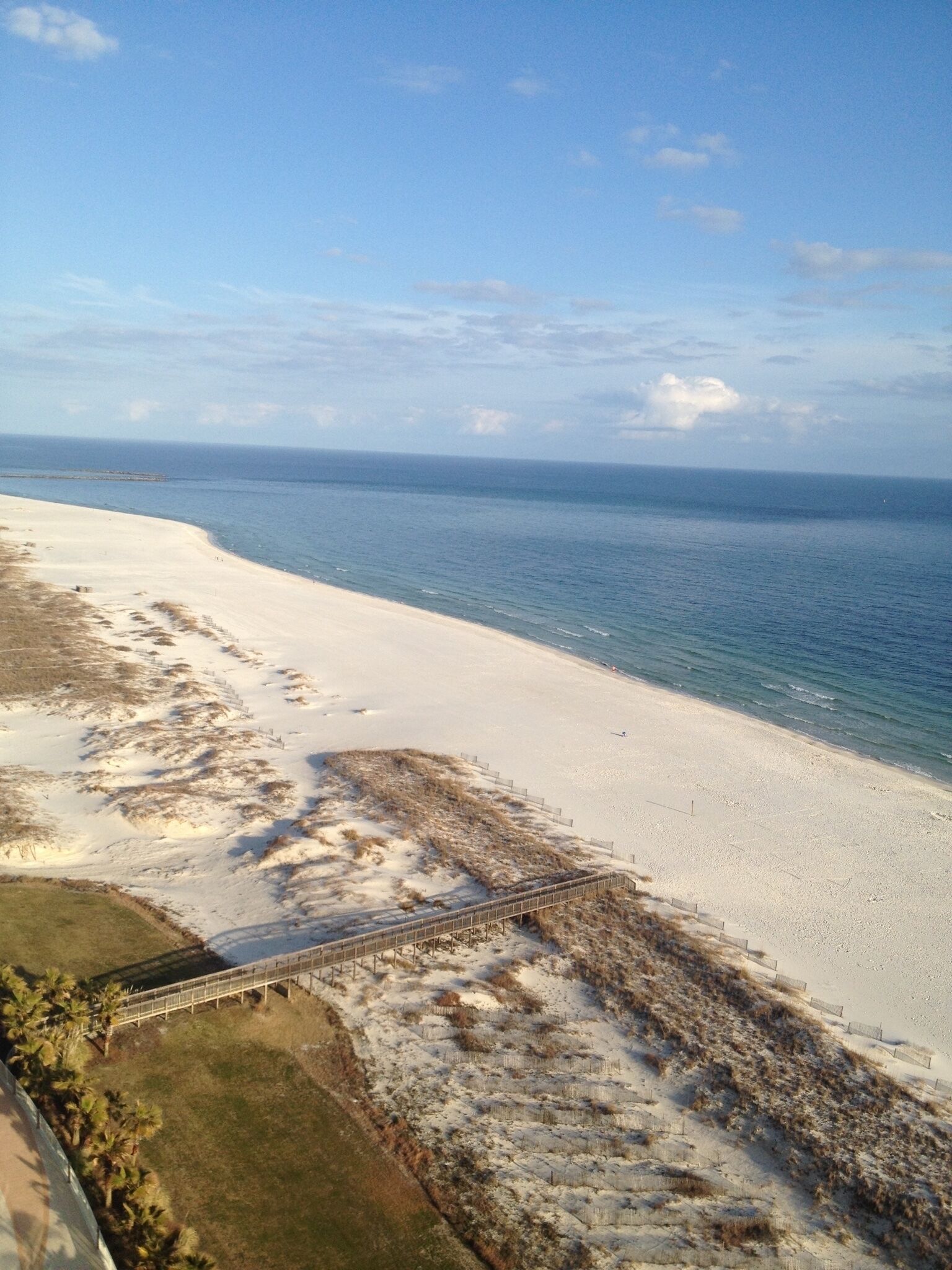 A beach with a sandy shore and a wooden walkway leading to the water.