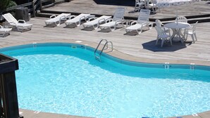 A swimming pool with lounge chairs and a table on a wooden deck. - Beautiful Oceanside Property W/Pool in Great Beach Location! (Corolla)