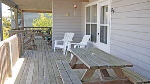 A covered porch with wooden benches and white chairs, a wooden table, and a white door with the number 4 on it. - Beautiful Oceanside Property W/Pool in Great Beach Location! (Corolla)