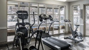 Ein Fitnessraum mit Cardiogeräten, großen Fenstern und Blick auf eine verschneite Landschaft.