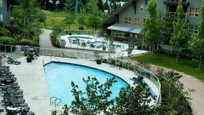 Ein Poolbereich mit Liegestühlen und einem kleinen Pool, umgeben von Gebäuden und Grünflächen.