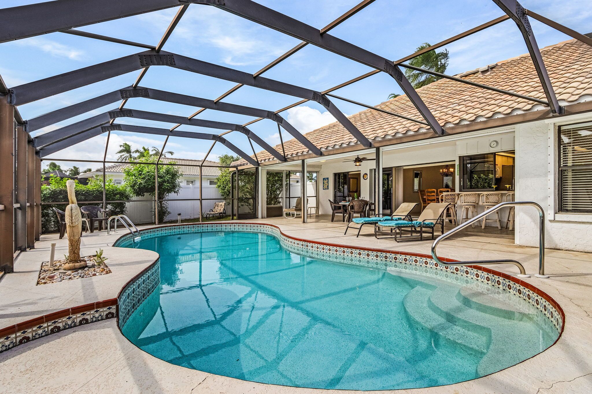 A swimming pool with a glass ceiling, surrounded by lounge chairs and a patio area.