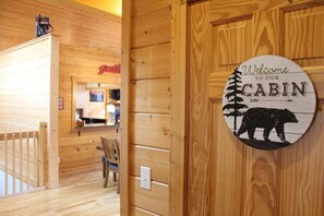 Cozy cabin interior with a welcoming sign and a comfortable seating area.