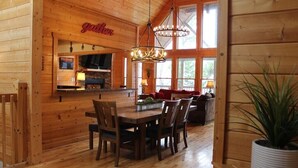 Un interior de madera con comedor, cocina y zona de estar con ventanas amplias.