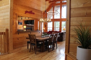 Gather around the dining table in this inviting space, featuring a kitchen and cozy seating area.