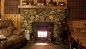 A cozy cabin interior with a stone fireplace, wooden walls, and a mounted deer head. - Sky View Log Cabin- Off the beaten trail yet close to all the main attractions! (Custer)