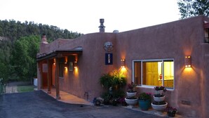 A stucco building with a covered entrance, outdoor lighting, and potted plants. - On the Pecos River in Pecos New Mexico (Pecos)