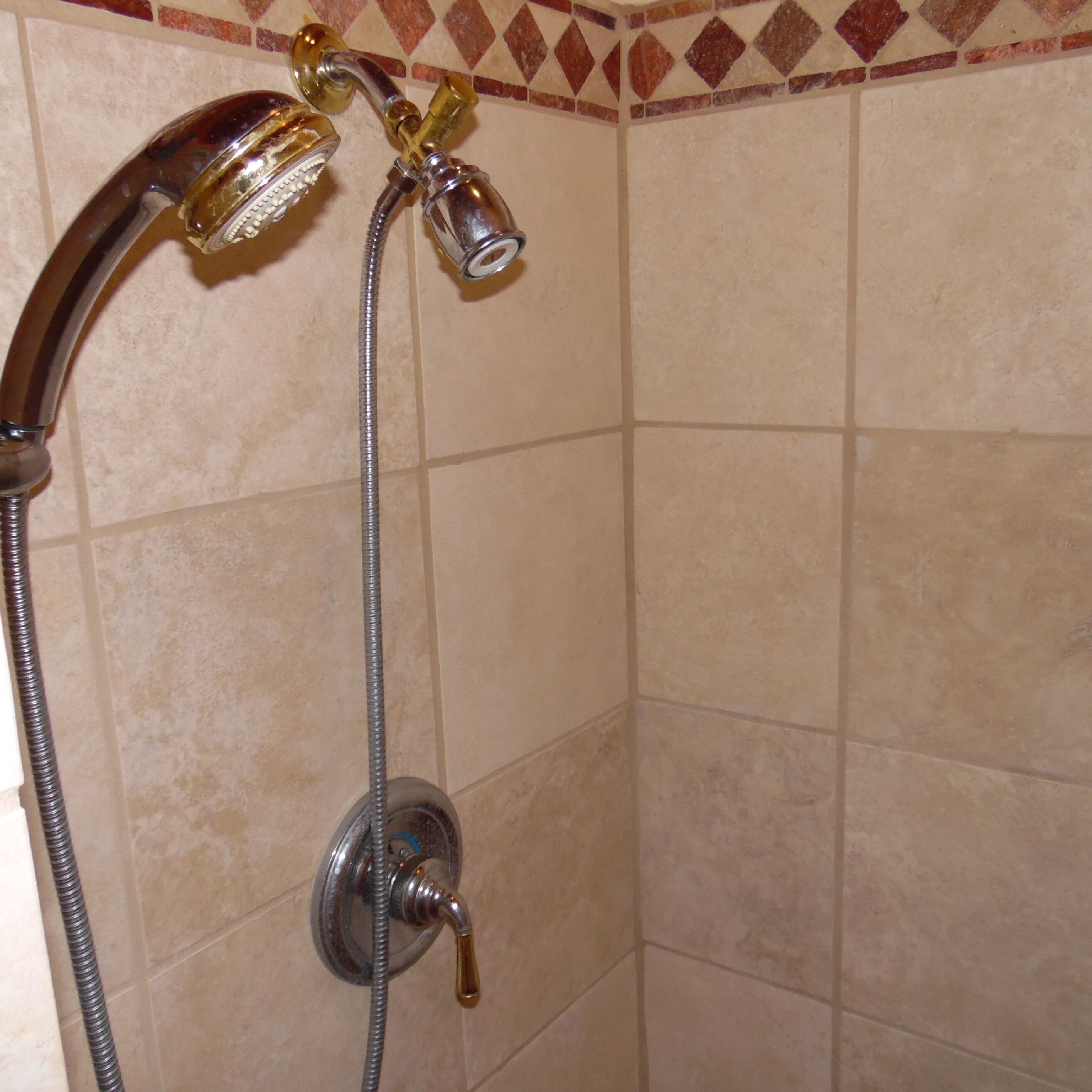 A shower with a handheld showerhead and a fixed showerhead, both attached to a flexible hose.