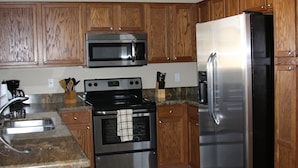 A kitchen with wooden cabinets, a stainless steel refrigerator, a microwave, an oven, and a granite countertop. - Near Cardinals Stadium, Texas Rangers Stadium, Golf, NASCAR and Hiking    (Surprise)
