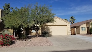 A residential house with a garage, a driveway, and a well-maintained garden with red flowers and a tree. - Near Cardinals Stadium, Texas Rangers Stadium, Golf, NASCAR and Hiking    (Surprise)