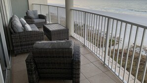 Ein Balkon mit Korbmöbeln und Blick auf das Meer bei Sonnenuntergang.