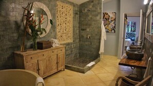 A bathroom with a bathtub, a wooden vanity with a mirror, a shower area with a stone wall, and a sink with a bowl basin. - 4BR Boutique Jungle Villa • Private Pool • Walkable Manuel Antonio (Manuel Antonio)