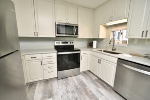A kitchen with white cabinets, a stainless steel microwave, an oven, and a dishwasher.