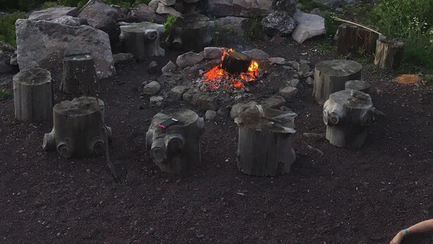 A campfire surrounded by rocks and wooden stumps in a forested area. - 4 Bedroom House - Great Views - Secluded Location (Jim Thorpe)