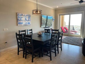 A dining area with a dark wooden table and chairs, a decorative light fixture, and a beach-themed artwork on the wall. - Oceanfront 4 bedroom 3 bath home for up to 10 guests -Your dream vacation awaits (Navarre)