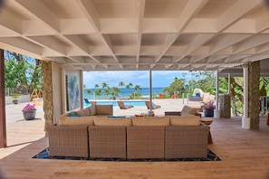 Un'area relax esterna coperta con vista sull'oceano e sulla piscina.