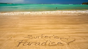 A beach with the words 'Surfer's Paradise' written in the sand.