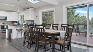 A modern kitchen with white cabinets, a central island, and a dining area with wooden chairs and a table.