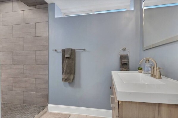 Une salle de bain moderne avec un grand miroir, un lavabo blanc et un porte-serviettes.