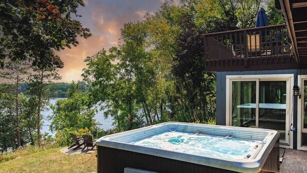 A hot tub on a deck with a view of a lake and trees.