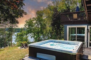 Un jacuzzi en una terraza con vistas a un lago y árboles.