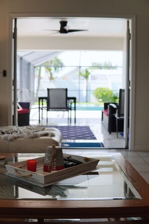 A glass-top table with a tray holding a candle, a remote, and a small decorative item. - HAPPYOURS Luxury Heated Pool, Hot tub No Additional Fees!!! @ Vanderbilt beach (Naples)