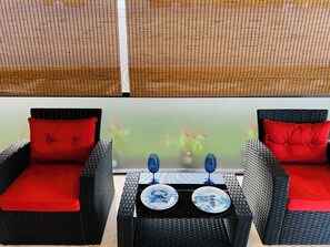 A balcony with wicker furniture, two red cushions, and a table with two blue glassware items. - HAPPYOURS Luxury Heated Pool, Hot tub No Additional Fees!!! @ Vanderbilt beach (Naples)