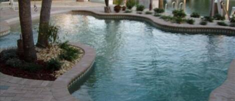 Relax by the serene pool surrounded by lush palm trees and tropical plants.
