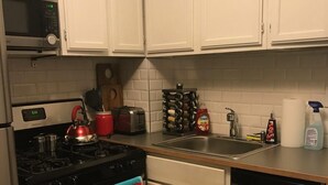 A kitchen with white cabinets, a microwave, a stove, a toaster, a sink, and a dishwasher. - Cozy Seward Home - Close To Everything (Minneapolis)