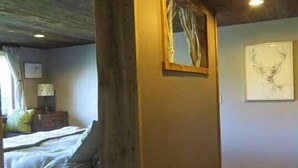 Een slaapkamer met een bed, nachtkastje, lamp en een ingelijst schilderij aan de muur.