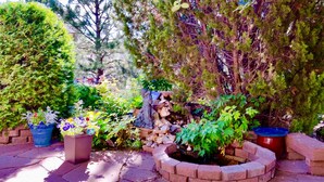 A garden with various potted plants, a brick planter, and a stone wall. - Charming Home quiet neighborhood lovely back yard 5 min from Garden of Gods (Colorado Springs)