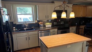 A kitchen with white cabinets, a wooden countertop island, a built-in oven, and a window with a view of a parked car. - Charming Home quiet neighborhood lovely back yard 5 min from Garden of Gods (Colorado Springs)